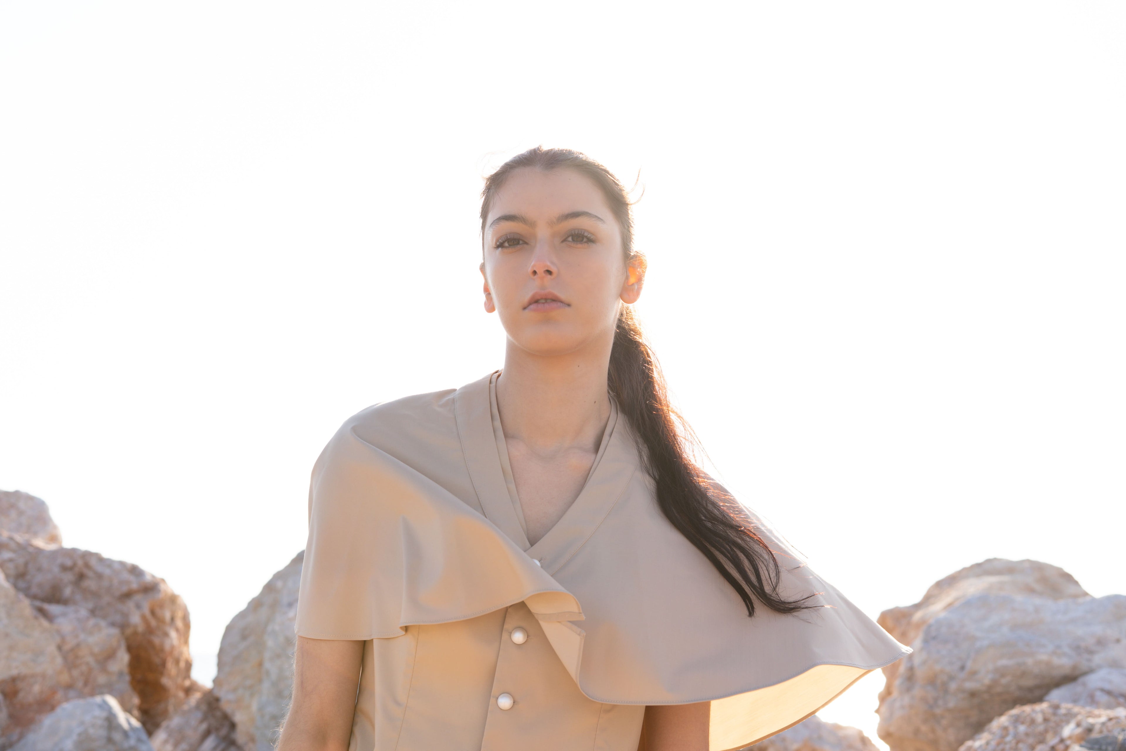 Bamboo Breeze vest and cape portrait, soft beige structured vest with flowing asymmetric cape, minimalist elegant summer look, warm sunset light styling