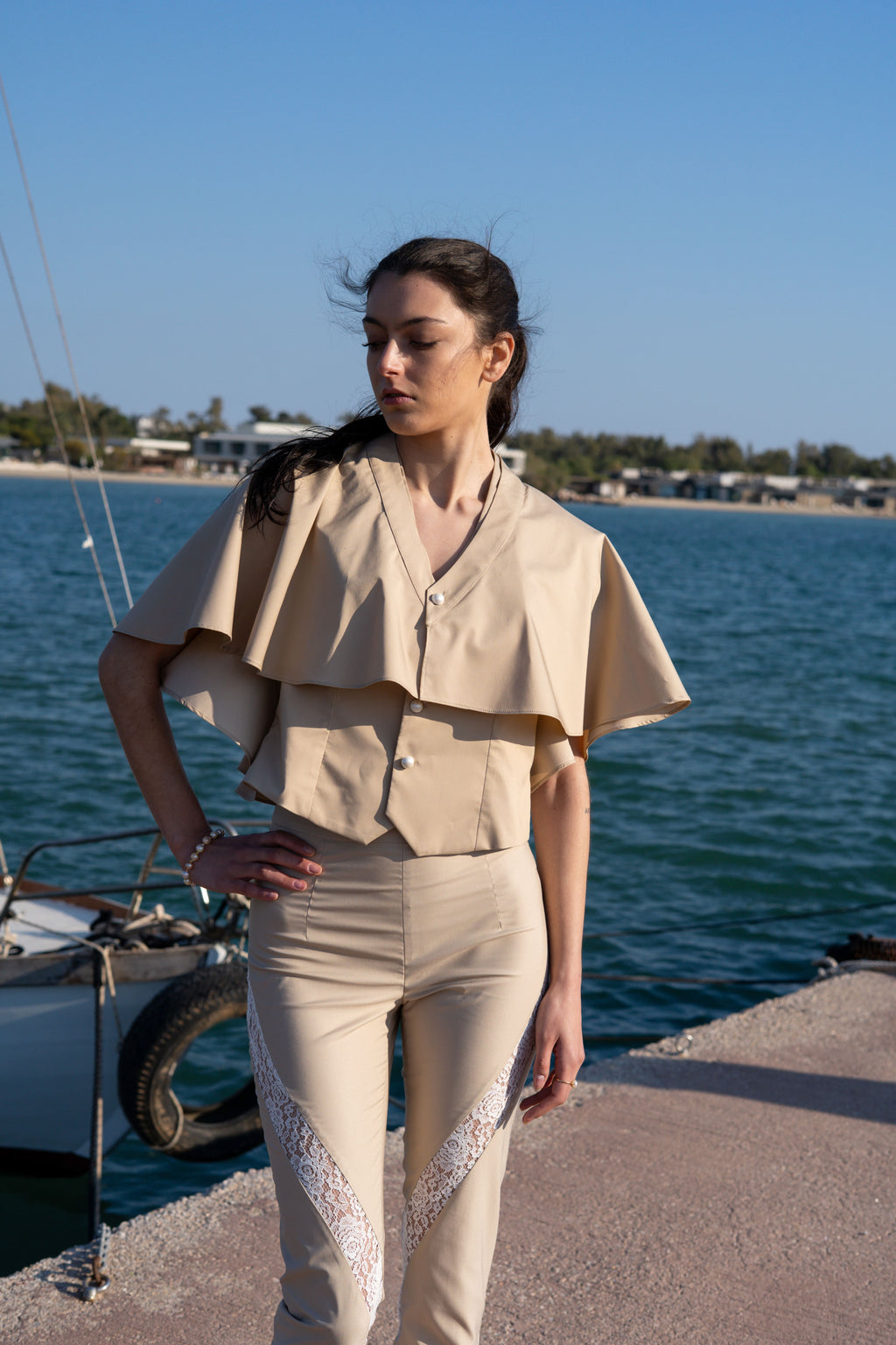 Julia Valas bamboo vest and detachable cape mid shot by the sea pearl buttons beige tailored set lace detail pants minimalist summer outfit coastal styling