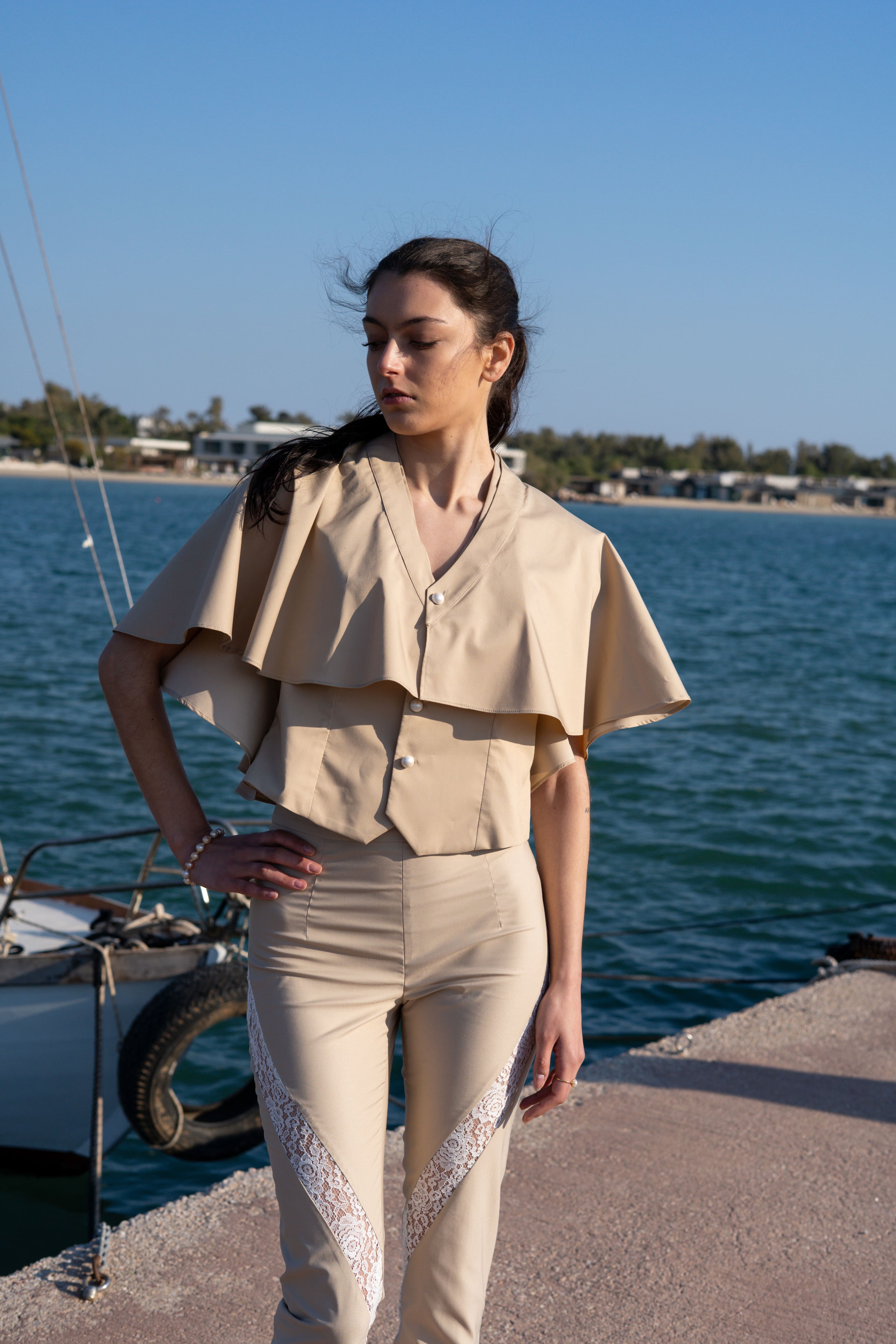 Julia Valas bamboo vest and detachable cape mid shot by the sea pearl buttons beige tailored set lace detail pants minimalist summer outfit coastal styling