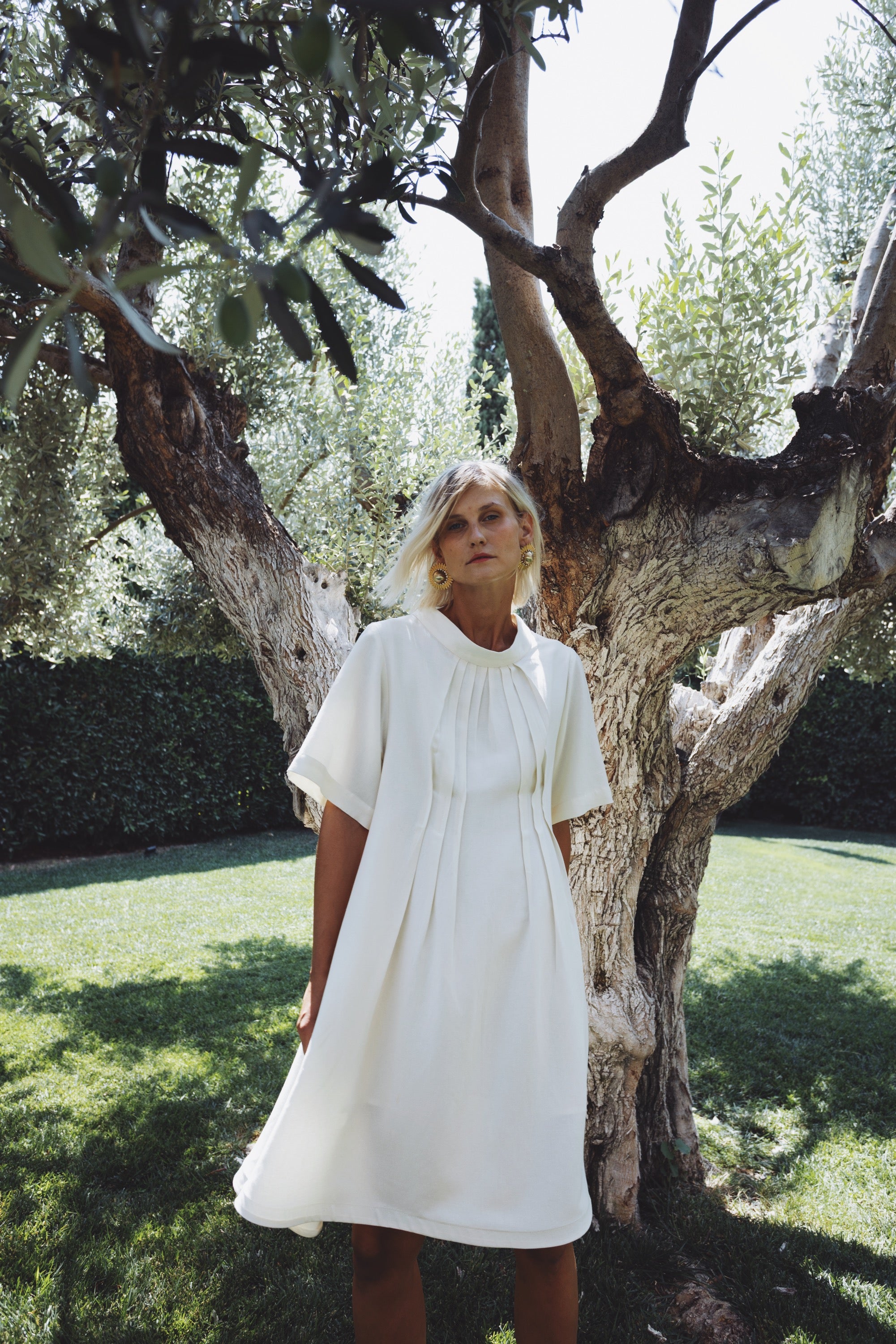 Cream linen-cotton dress with soft pleats in natural outdoor setting