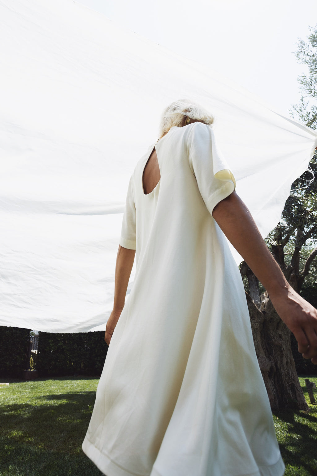 Cream linen-cotton dress with open back and flowing silhouette in motion