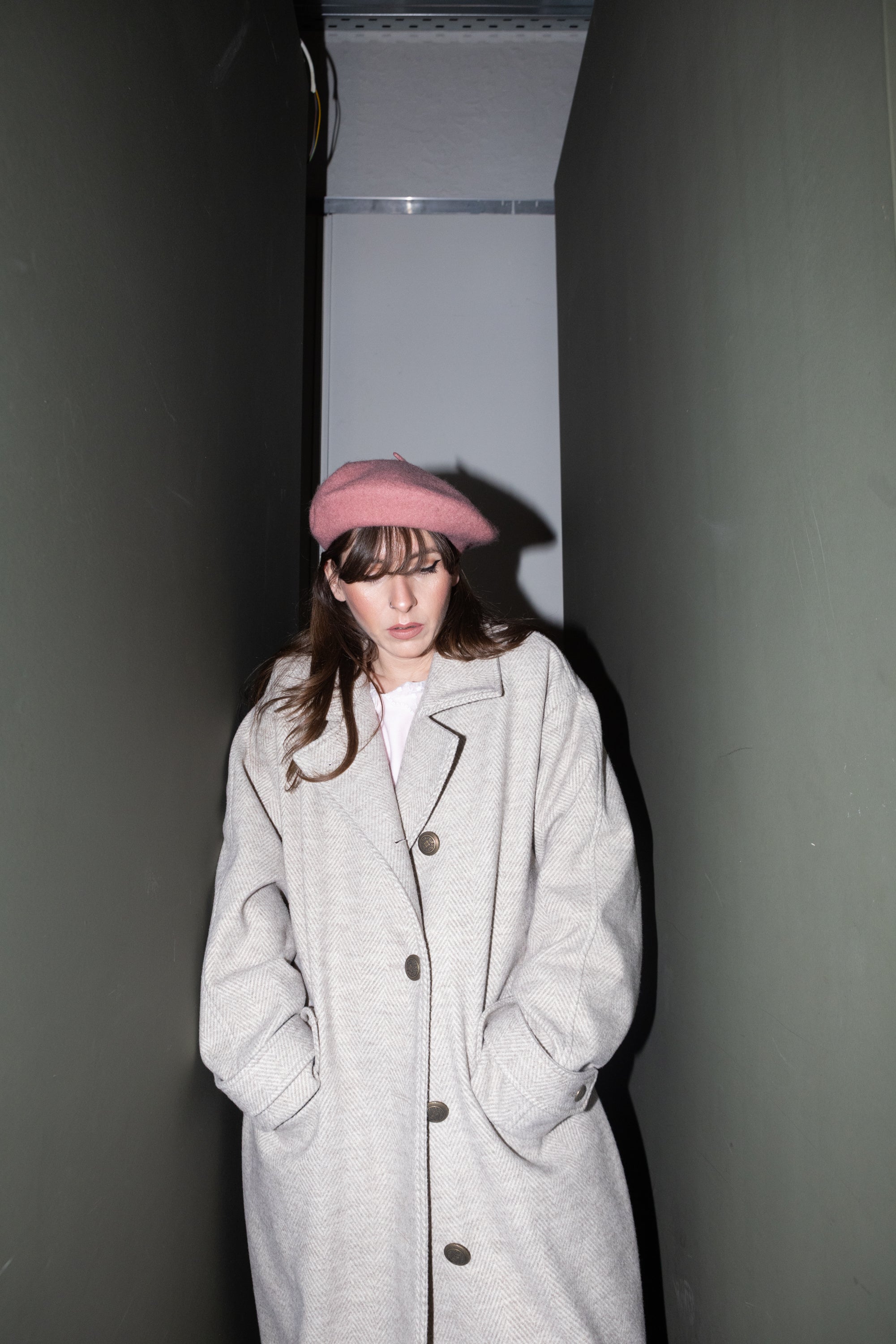 Convertible Collar Coat – oversized wool herringbone coat, maxi-length front view, hands in pockets, minimal corridor setting, pink beret styling, FW25-26 Julia Valas.