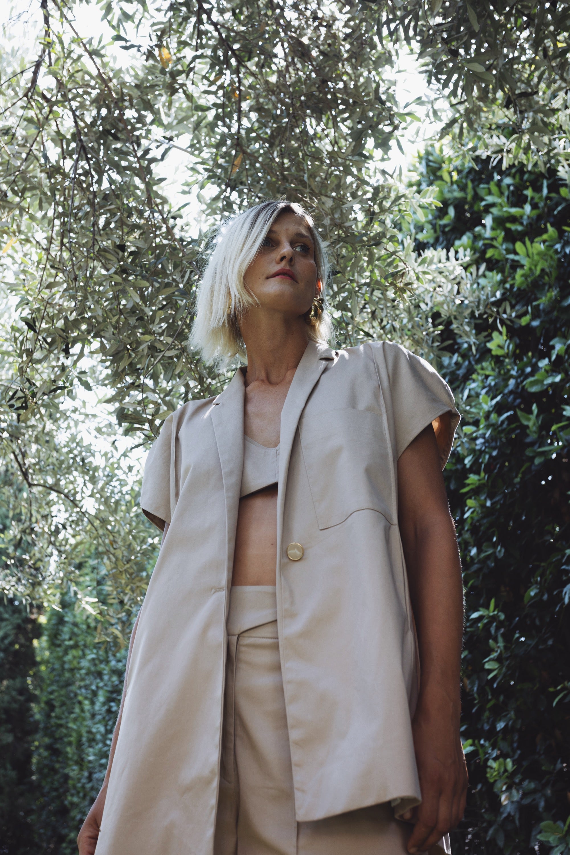 Woman wearing oversized cotton Halo blazer with short voluminous sleeves under olive trees
