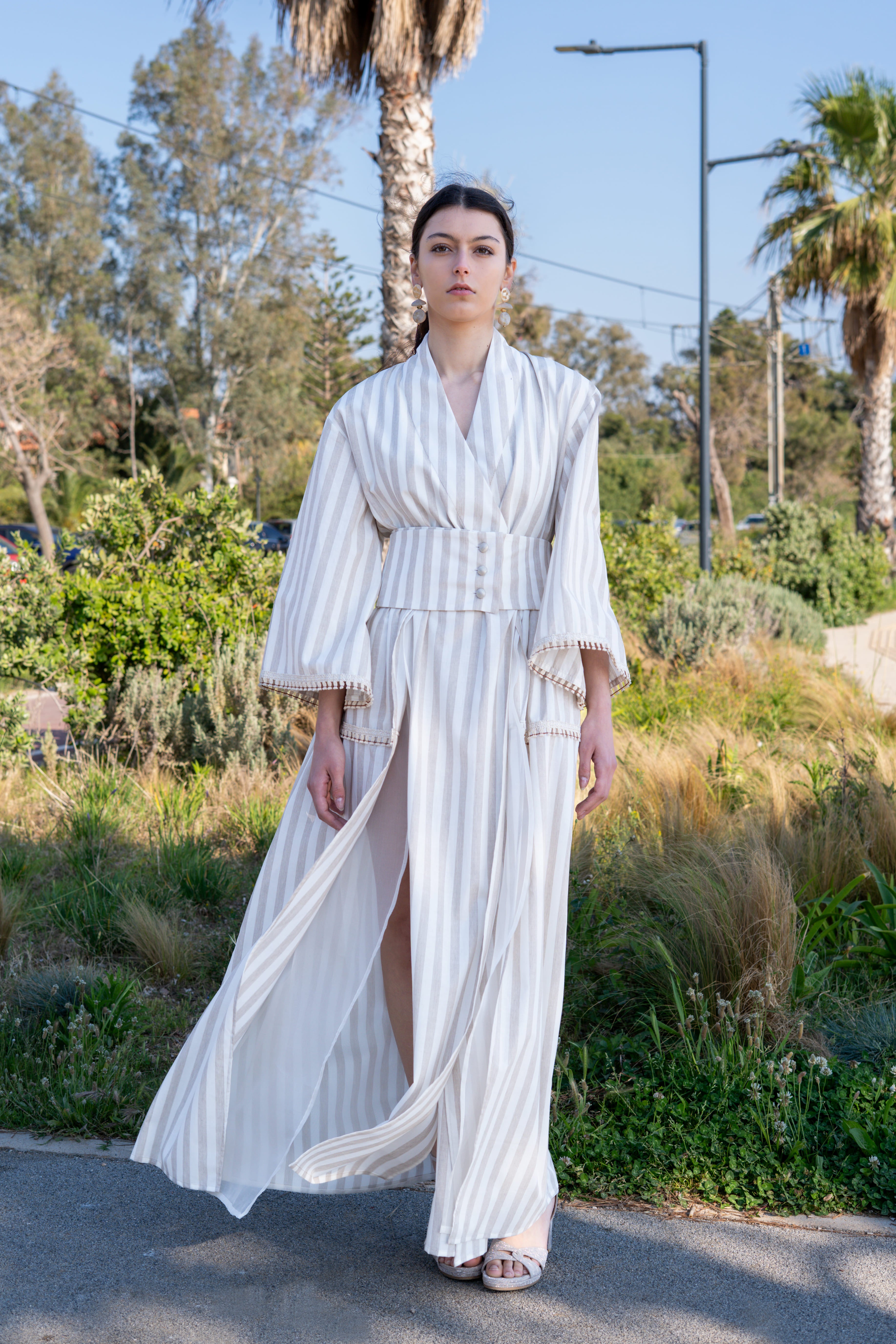 Striped cotton kimono dress walking outdoors with wide belt, flowing skirt and high slit, lightweight movement silhouette