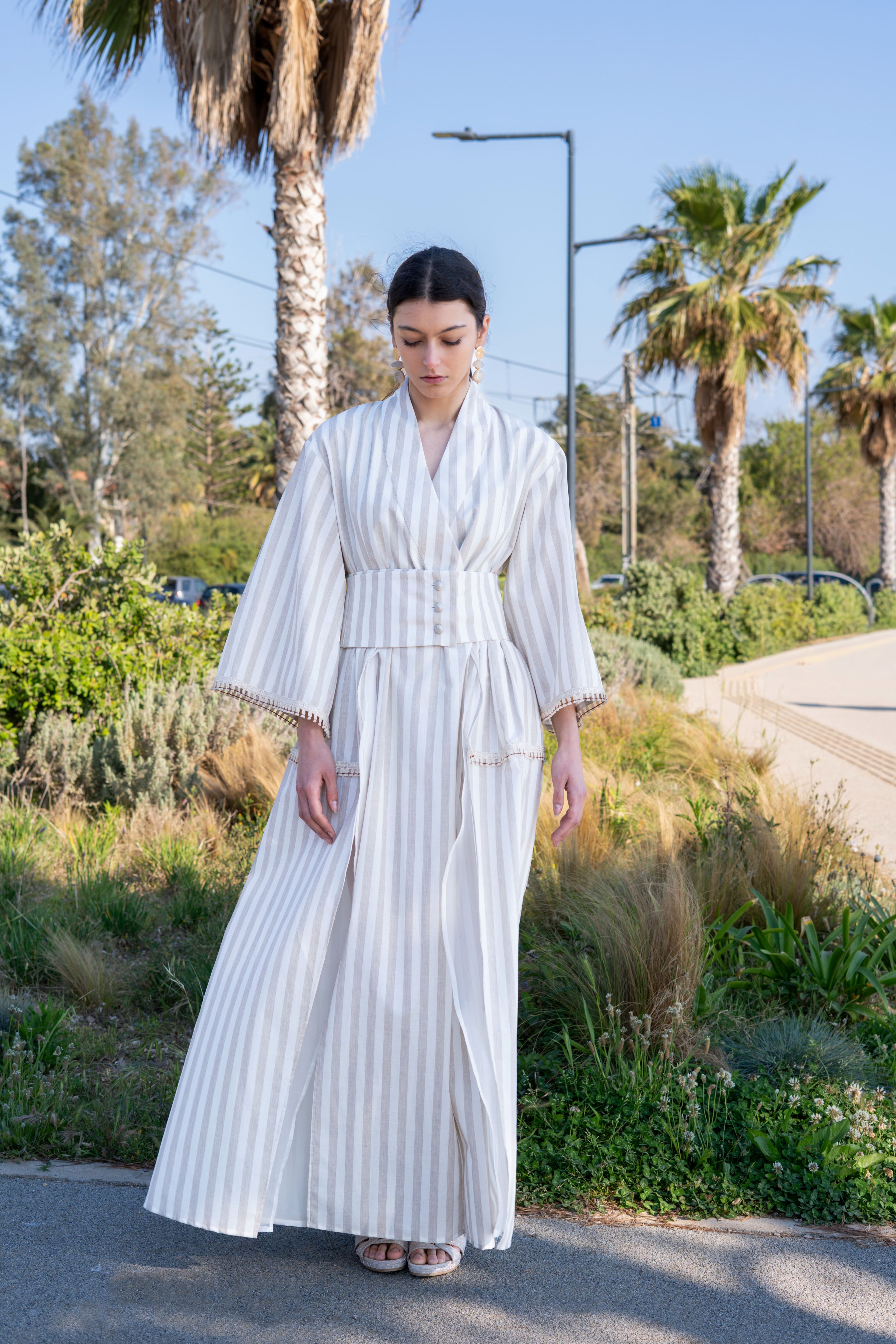 Striped cotton kimono dress with wide sleeves, belted waist and front slits, full body front view in natural outdoor setting