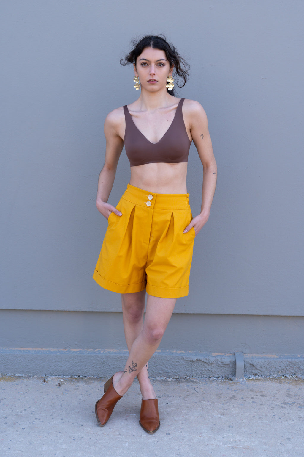 Canary yellow high-waisted tailored bermuda shorts with front pleats and double button closure, styled full look front view