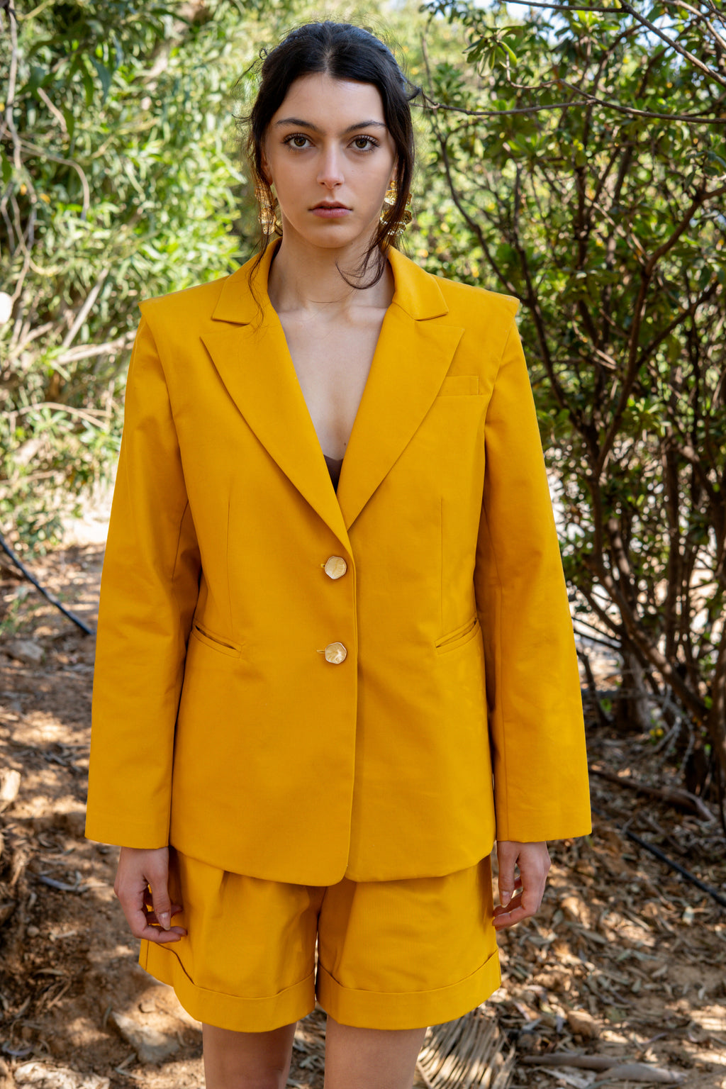 canary yellow tailored blazer with structured shoulders front view in natural outdoor light with matching bermuda shorts