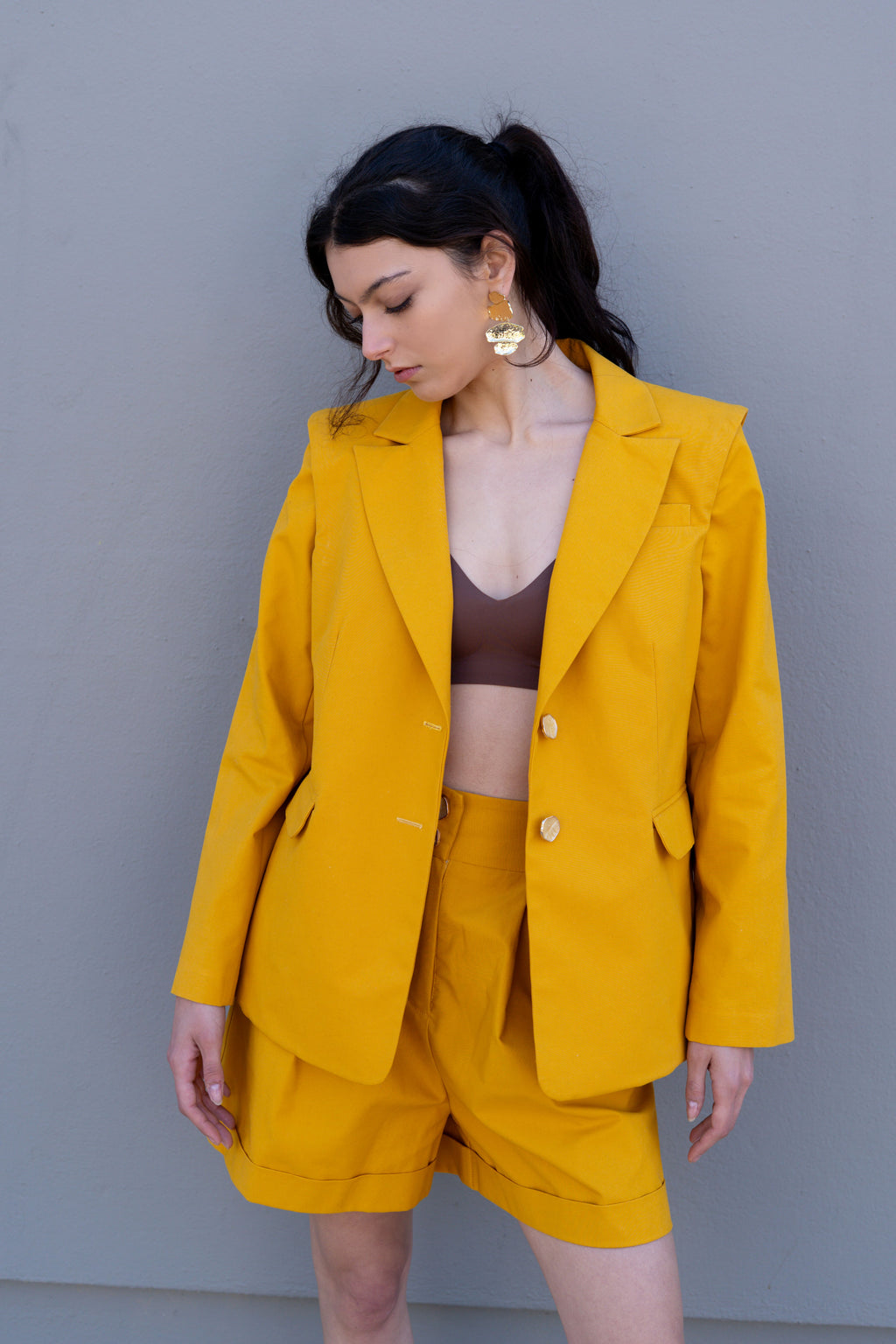 canary yellow tailored blazer with structured shoulders worn open styled with bralette and matching bermuda shorts