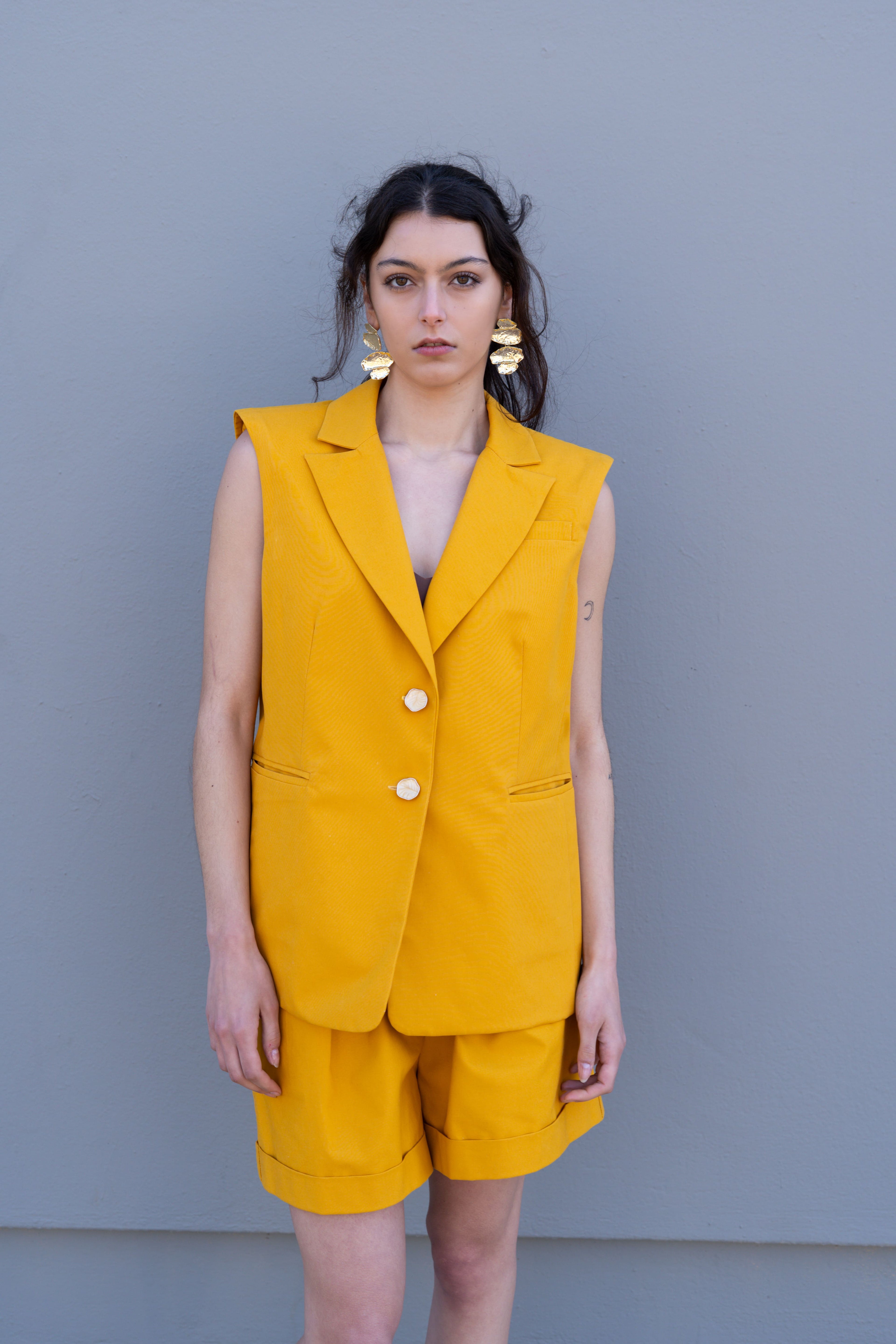 Canary yellow tailored vest with sharp shoulders and double button front, styled with matching bermuda shorts, clean front view