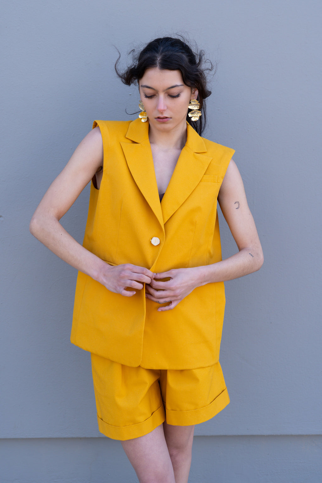 Canary yellow tailored vest with structured shoulders and front button closure, styled with matching bermuda shorts, front view