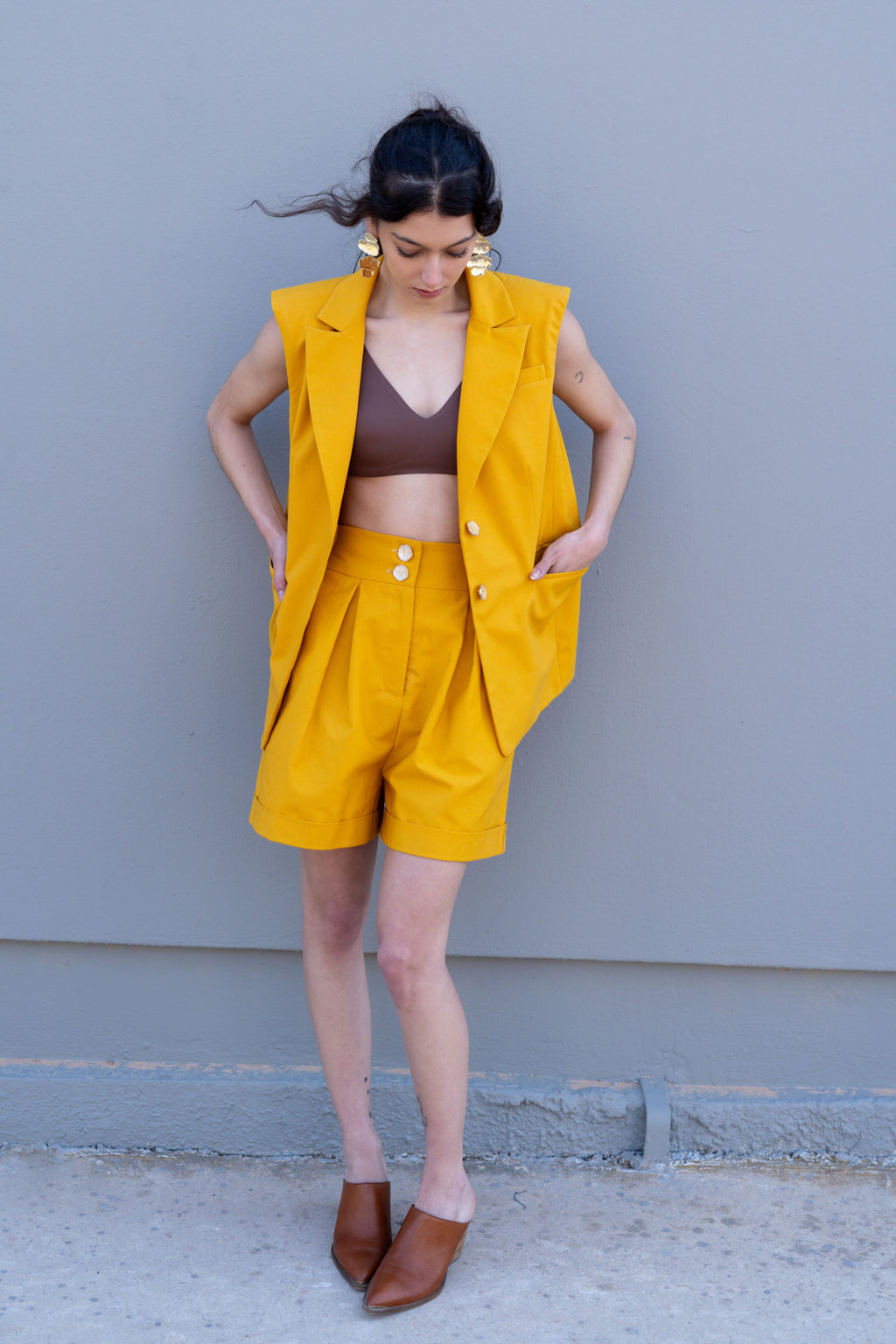 Canary yellow tailored bermuda shorts with front pleats and high waist, styled with matching vest, relaxed A-line silhouette