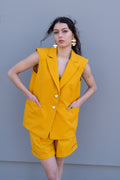 Canary yellow tailored vest with structured shoulders and front pockets, worn as a summer set with matching bermuda shorts