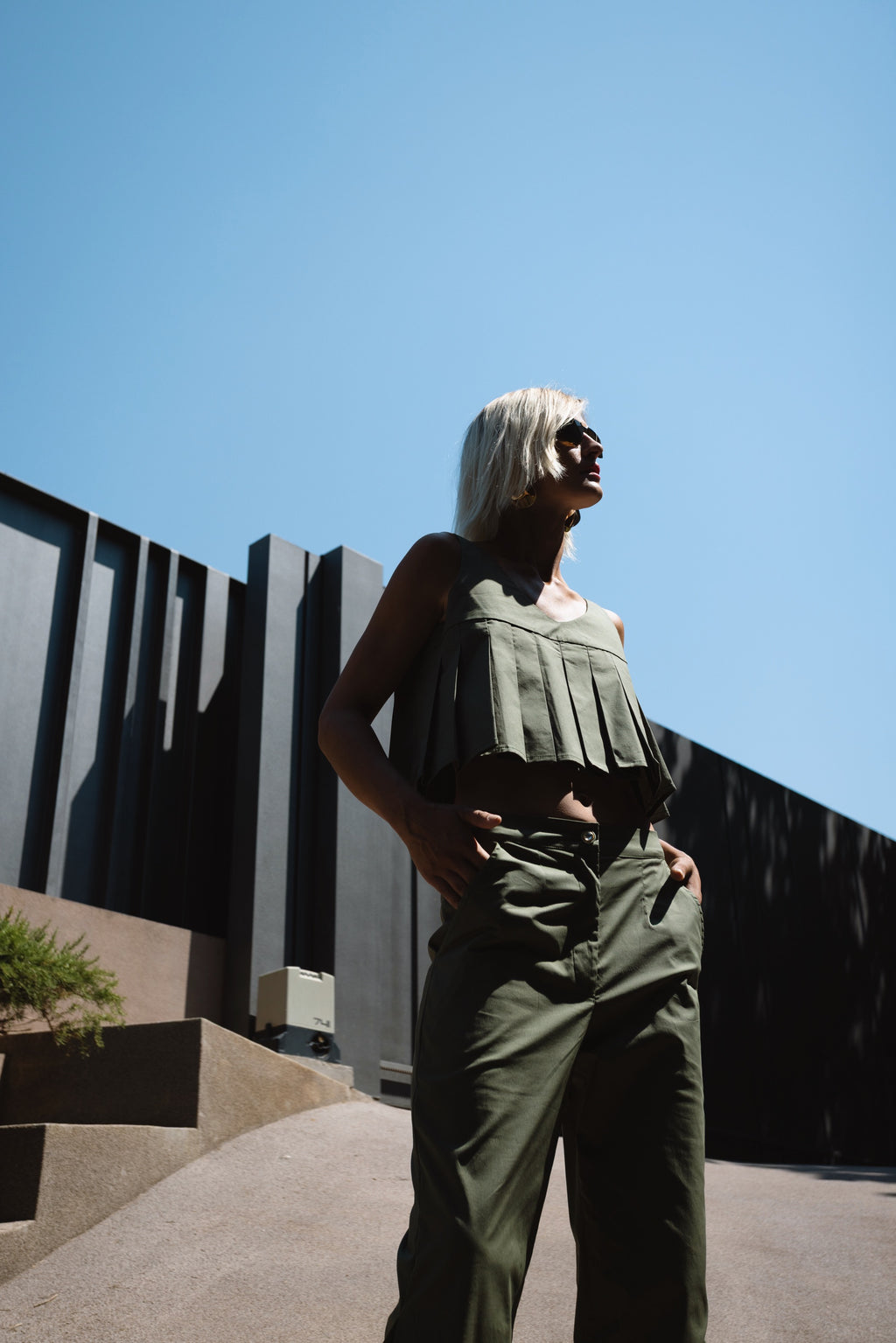 Julia Valas Elia Top with olive capri trousers matching set in strong sunlight architectural setting outdoors