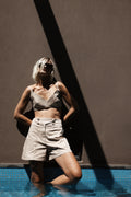 Beige high-waisted tailored bermuda with front button detail styled with Halo bralette in the pool – Julia Valas