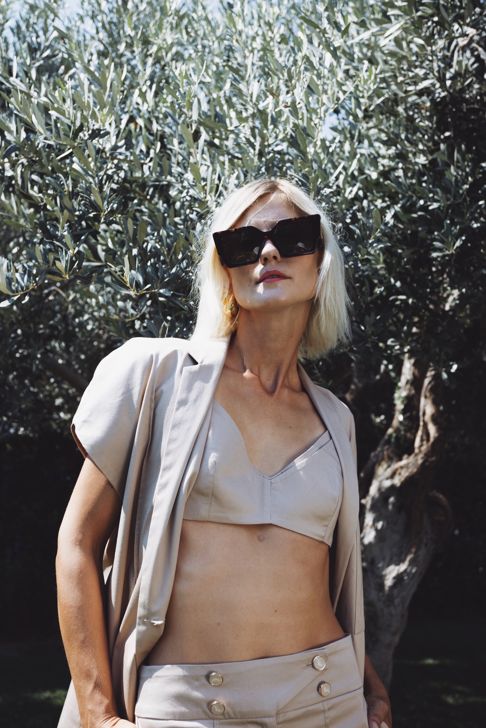 Julia Valas Halo set in beige cotton featuring bralette, blazer and shorts, worn outdoors under olive trees