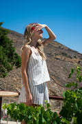 Side view of the Julia Valas Sleep-to-Seaside Set in Sand Stripe featuring a striped linen camisole with double-layered bust and relaxed shorts in a sunlit Cycladic landscape.