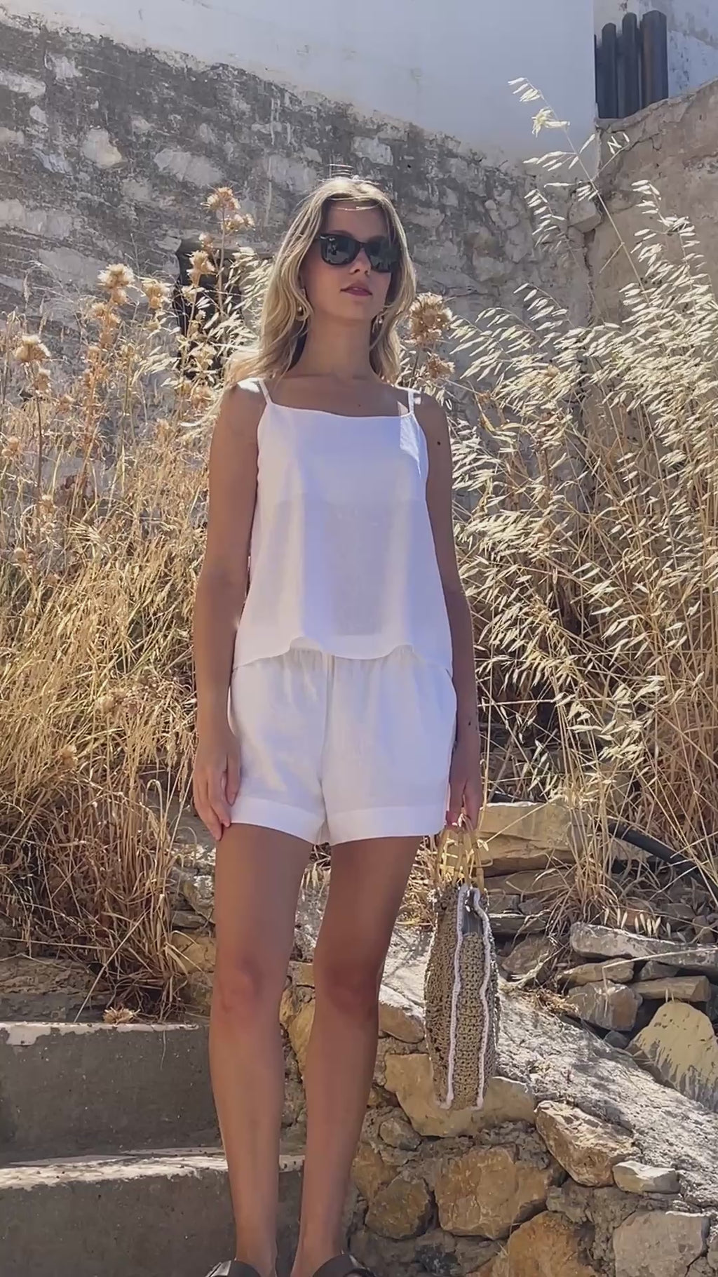 Video of a model walking in the Julia Valas Sleep-to-Seaside Set in Off White, featuring a lightweight linen camisole and relaxed shorts in a sunlit Cycladic setting.