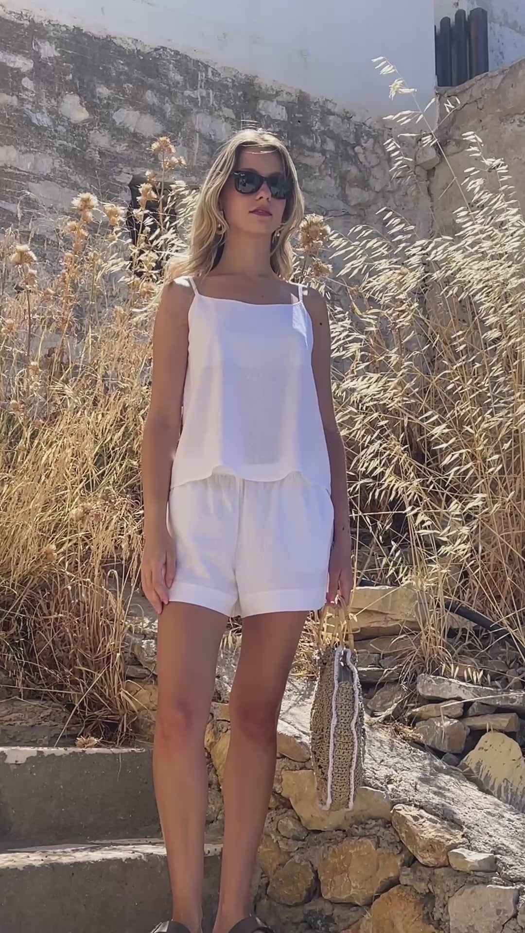 Video of a model walking in the Julia Valas Sleep-to-Seaside Set in Off White, featuring a lightweight linen camisole and relaxed shorts in a sunlit Cycladic setting.