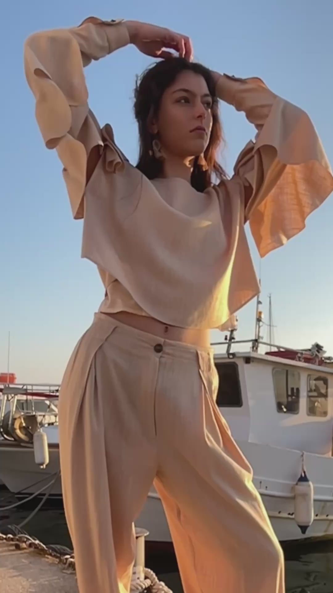 Relaxed linen viscose ruffled top with detachable sleeves and flowing draped details paired with pleated loose-fit trousers, fresh linen natural fabrics resort womenswear by Julia Valas - video