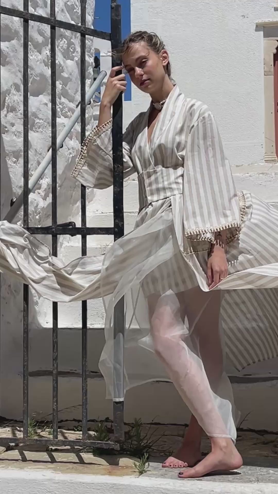 Julia Valas Hour Kimono Dress in Sand Stripe cotton, front view featuring flowing kimono sleeves and skirt in the sunlit streets of Syros, Greece.