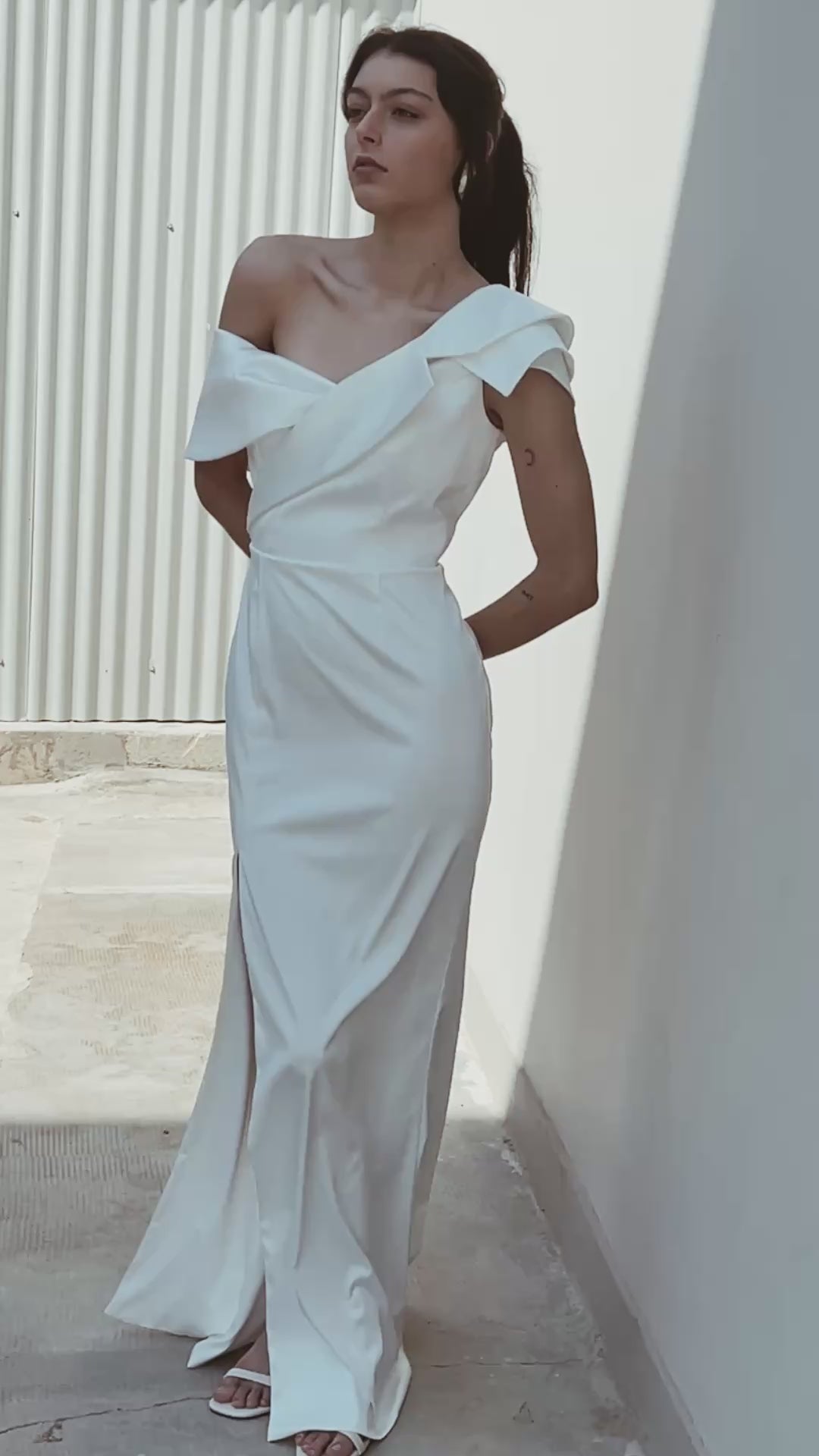 one-shoulder bridal gown with deconstructed lapel neckline and front slit elegant fit standing at the shadow sun