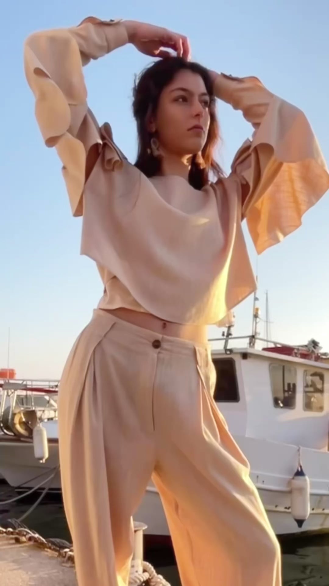 Relaxed linen viscose ruffled top with detachable sleeves and flowing draped details paired with pleated loose-fit trousers, fresh linen natural fabrics resort womenswear by Julia Valas - video