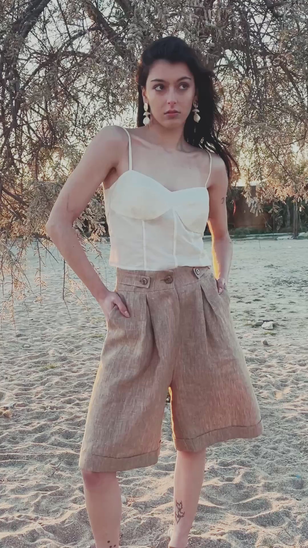 Smart Volume bermuda pants front and back view windy video with high-waisted fit and sculptural volume, pleated tailored design in textured linen fabric, elegant summer silhouette