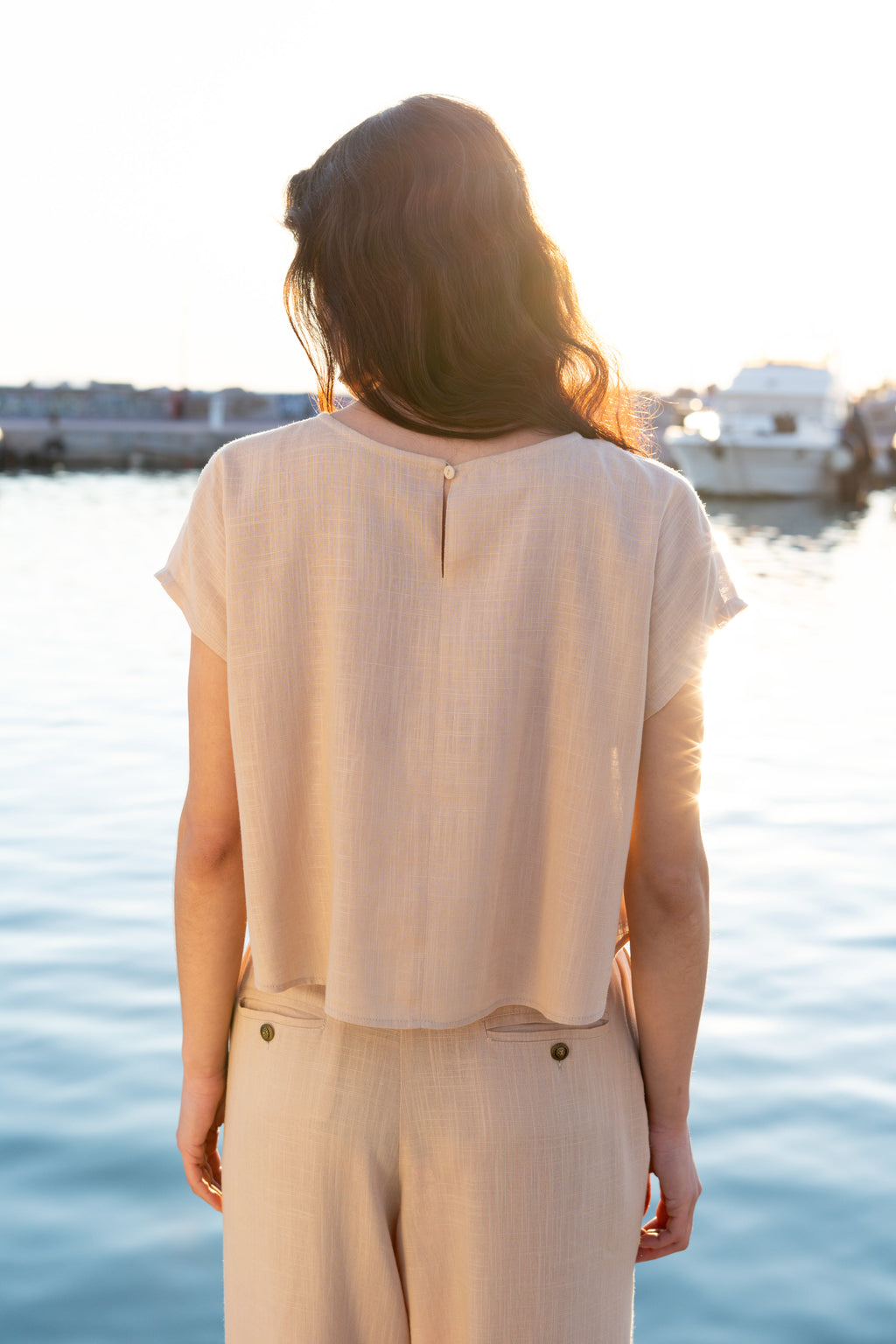 Back view of minimal linen viscose cropped top styled sleeveless with detachable ruffle sleeves removed, relaxed summer silhouette with soft drape by Julia Valas