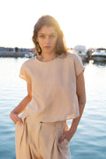 Minimal linen viscose cropped top styled sleeveless with detachable ruffle sleeves removed, relaxed summer silhouette paired with pleated loose trousers by Julia Valas