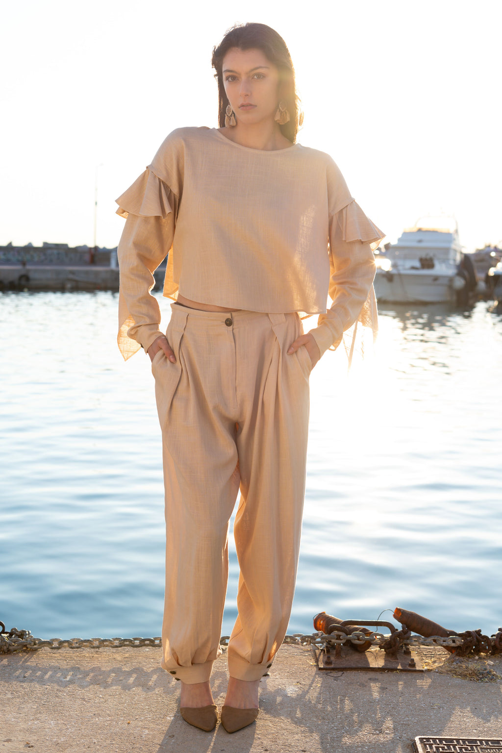 Relaxed linen viscose ruffled top with detachable sleeves and flowing draped details paired with pleated loose-fit trousers, minimal resort womenswear by Julia Valas