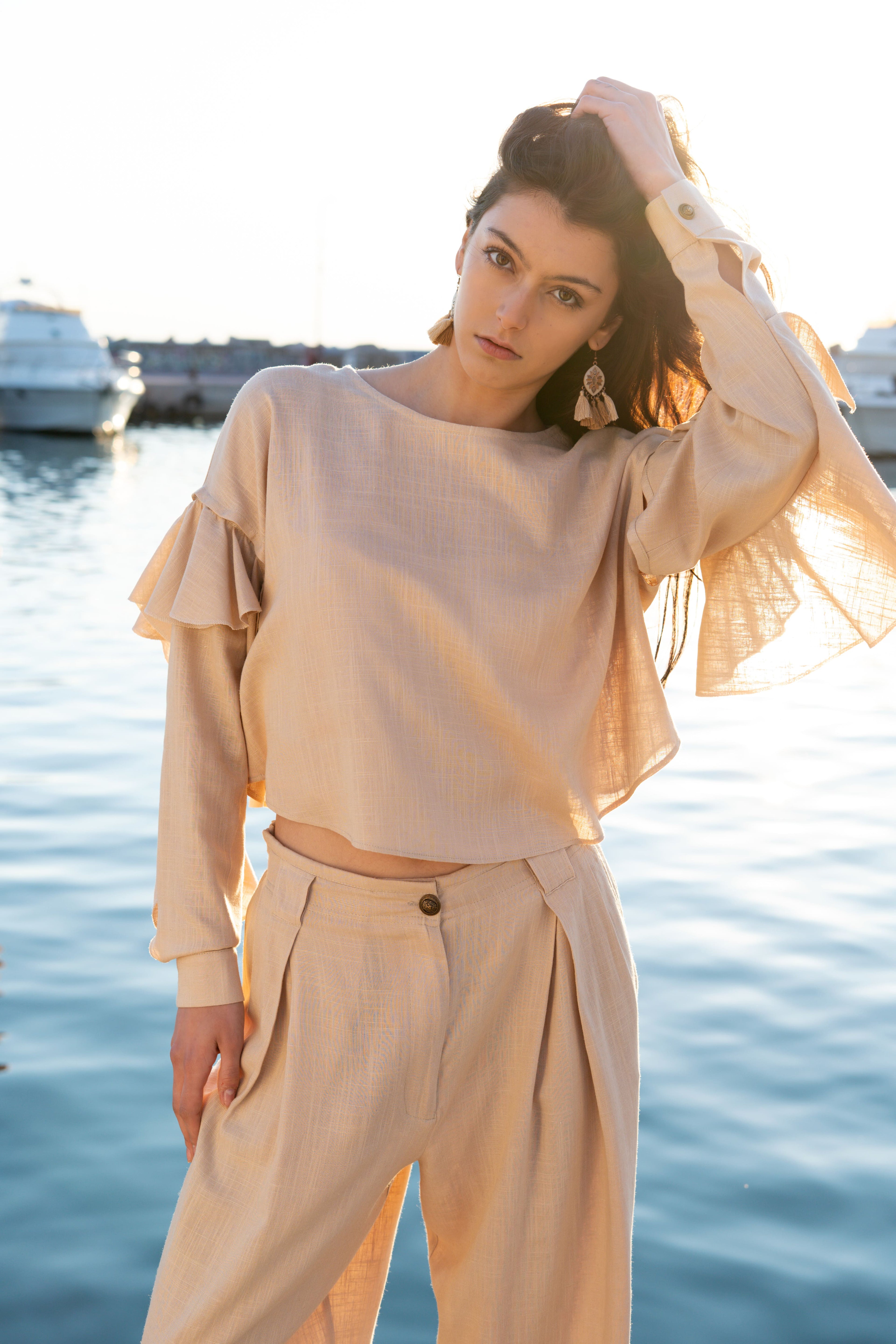 Soft linen viscose ruffled crop top with detachable draped sleeves and relaxed fit styled with pleated loose trousers, elegant resort womenswear by Julia Valas