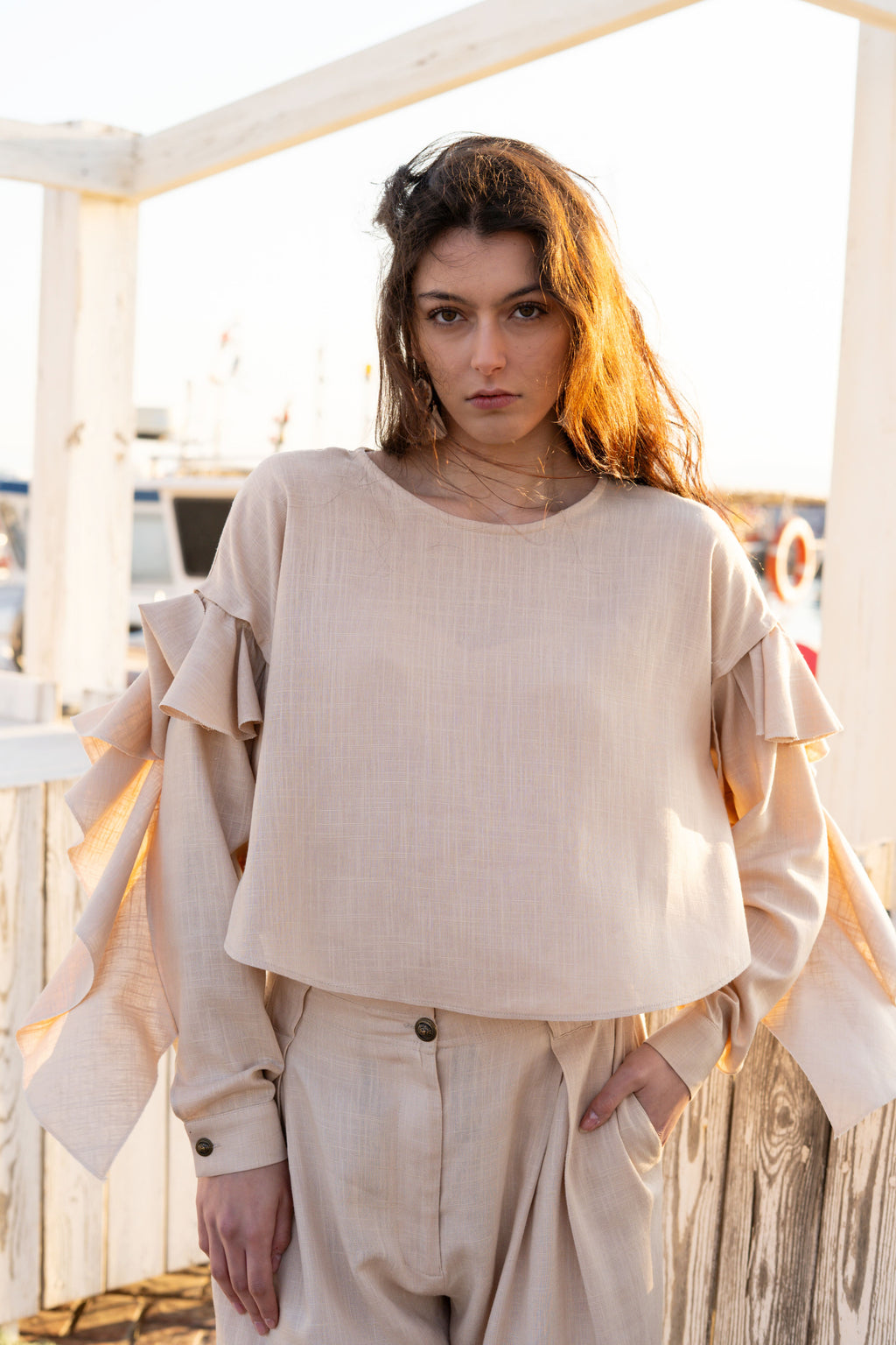 Relaxed linen viscose ruffled top with detachable statement sleeves, soft oversized silhouette and layered draped details in warm sunset light