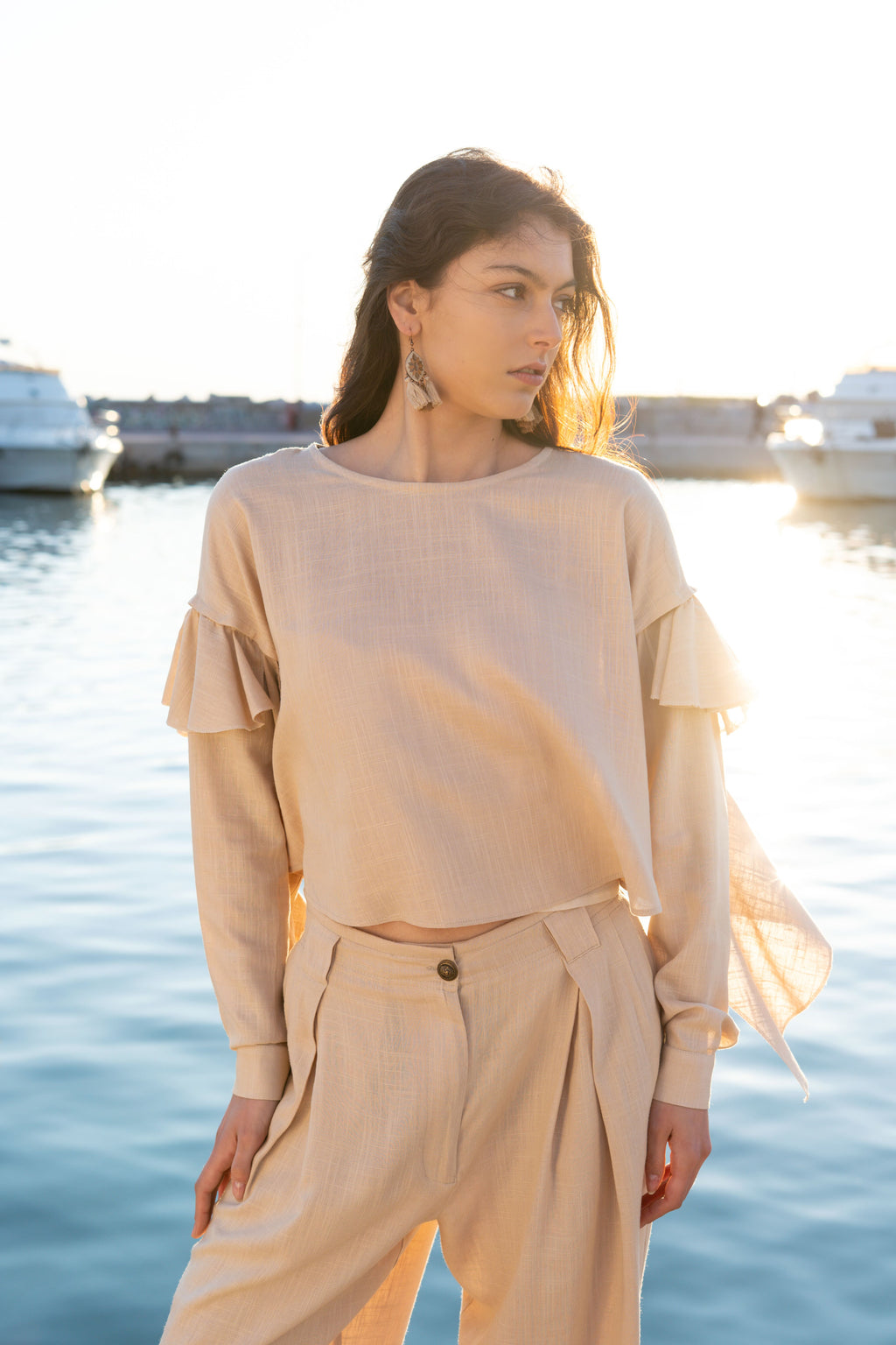 Ruffled linen viscose top with detachable sleeves and layered ruffle detail, relaxed summer silhouette in soft sunset light