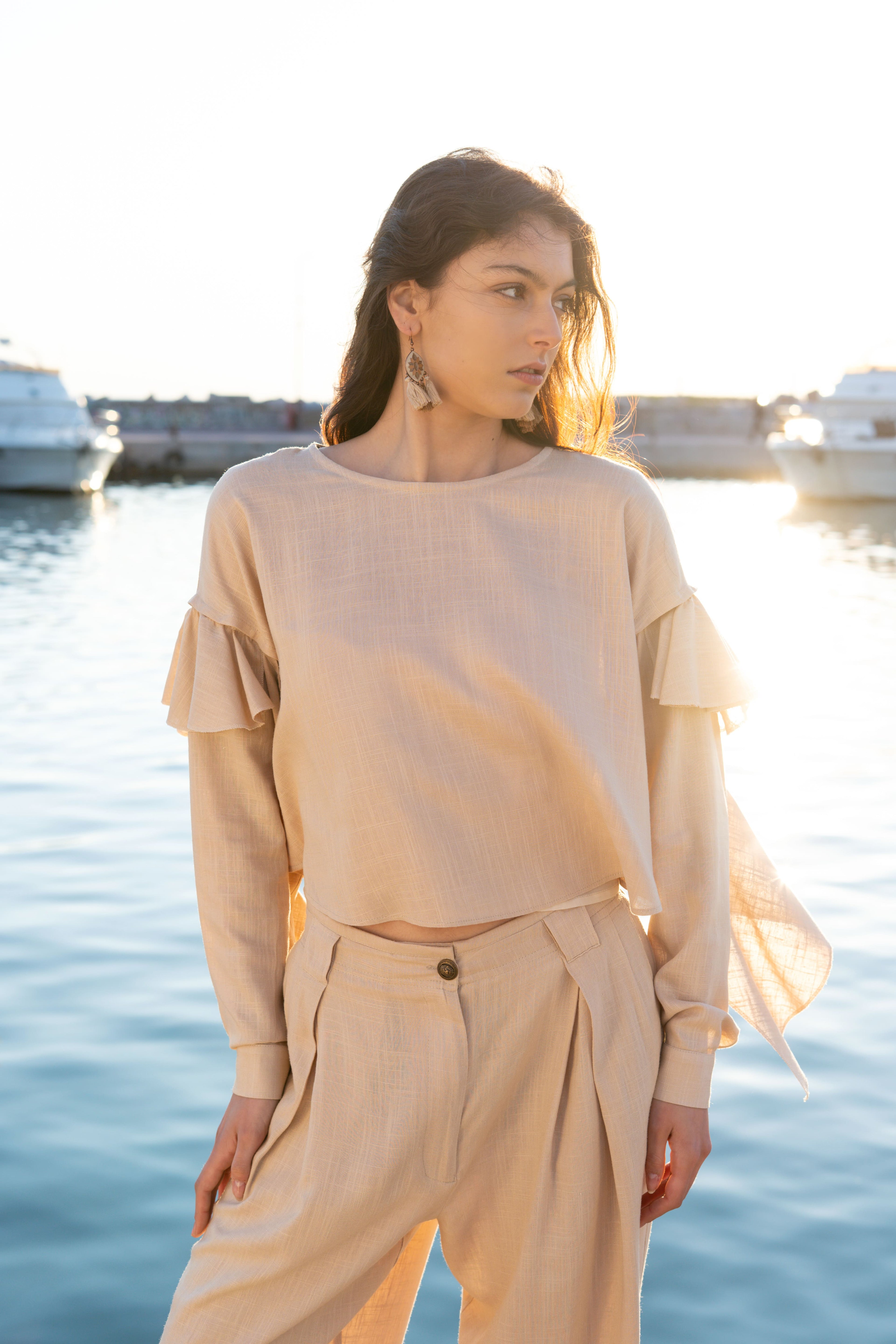 Ruffled linen viscose top with detachable sleeves and layered ruffle detail, relaxed summer silhouette in soft sunset light