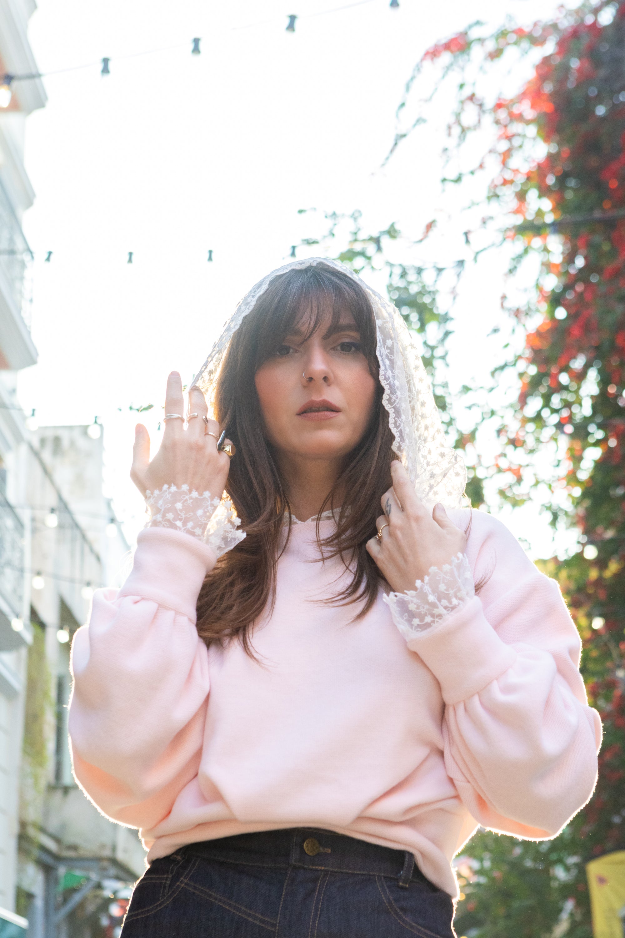 Woman wearing soft pink cotton lace hoodie with lace hood and cuffs, front view portrait, outdoor natural light, Julia Valas