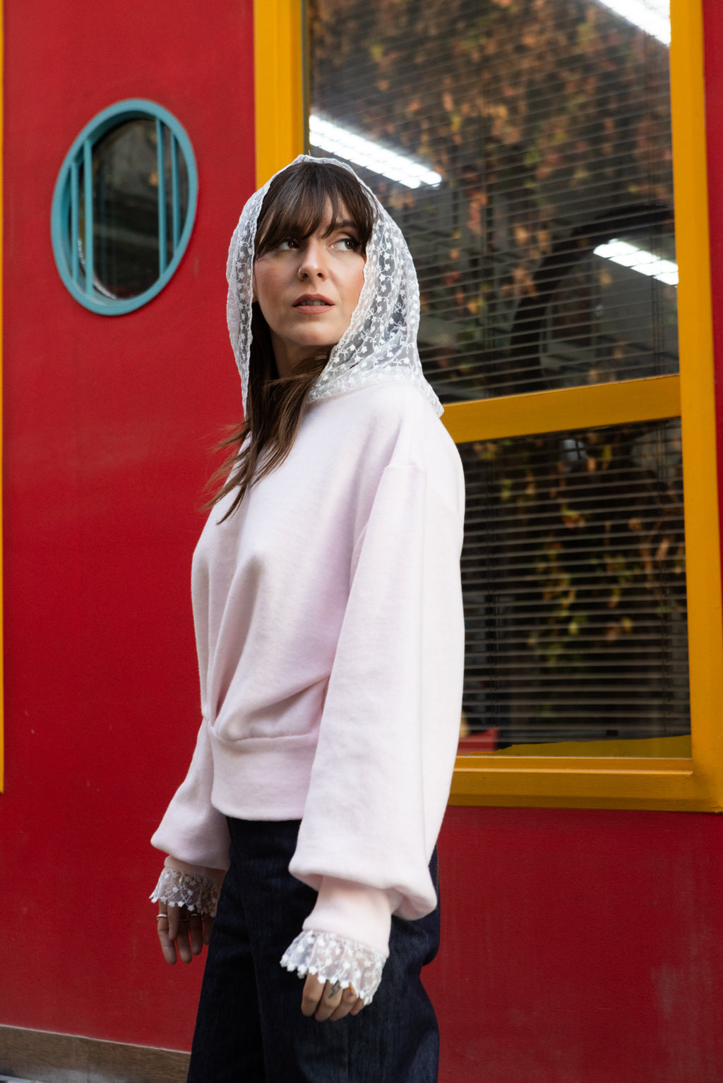 Woman wearing a soft pink cotton lace hoodie with lace hood and cuffs, side profile, Julia Valas