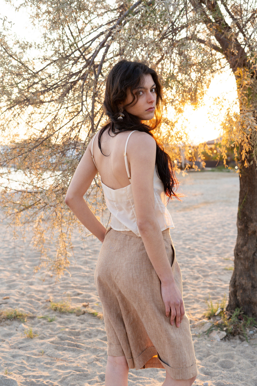 Smart Volume bermuda pants back view with high-waisted fit and sculptural volume, pleated tailored design in textured natural fabric, elegant summer silhouette