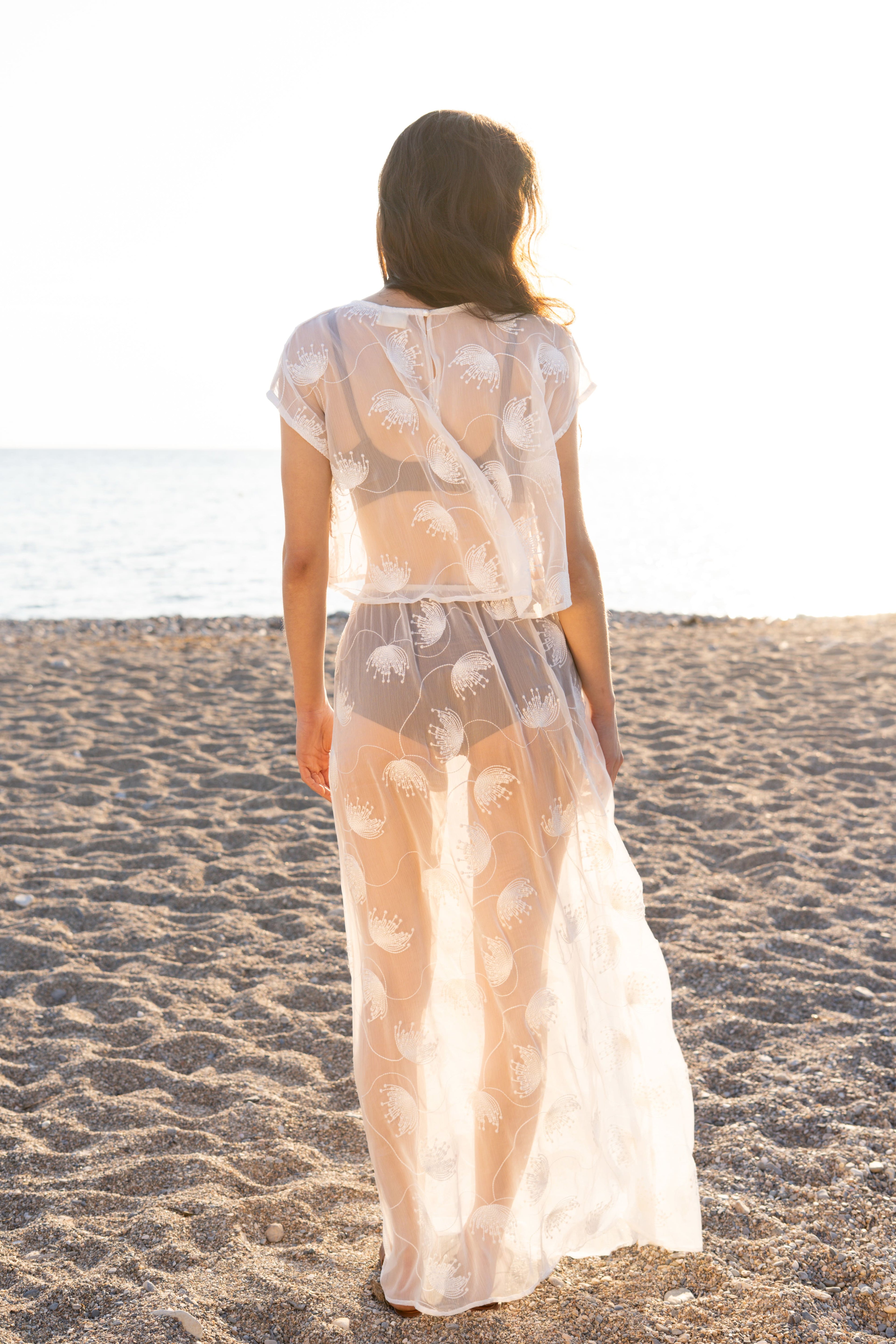 Back view of the Thalassa Sheer Set with embroidered transparent top and flowing sheer maxi skirt, airy coastal womenswear silhouette at golden hour by Julia Valas