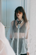 Sheer silk organza shirt with pearl buttons and structured collar, styled with neck bow detail and lace layering underneath, Julia Valas